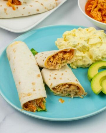 Crock Pot Buffalo Chicken Wraps served with ranch dressing on a dinner plate.