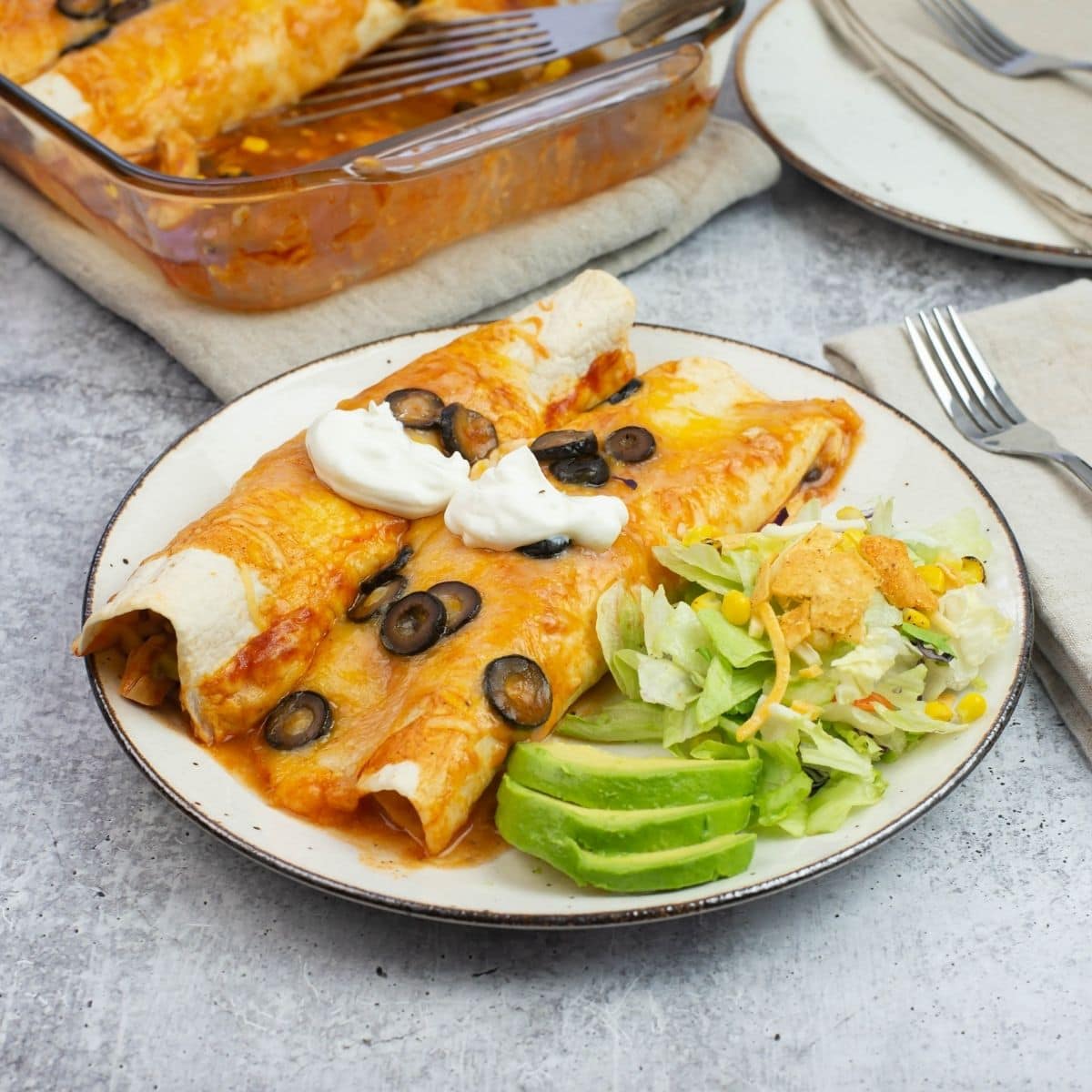 A serving of enchiladas on a plate with a side salad.