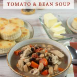 Vertical image of soup bowl with biscuits in the background.