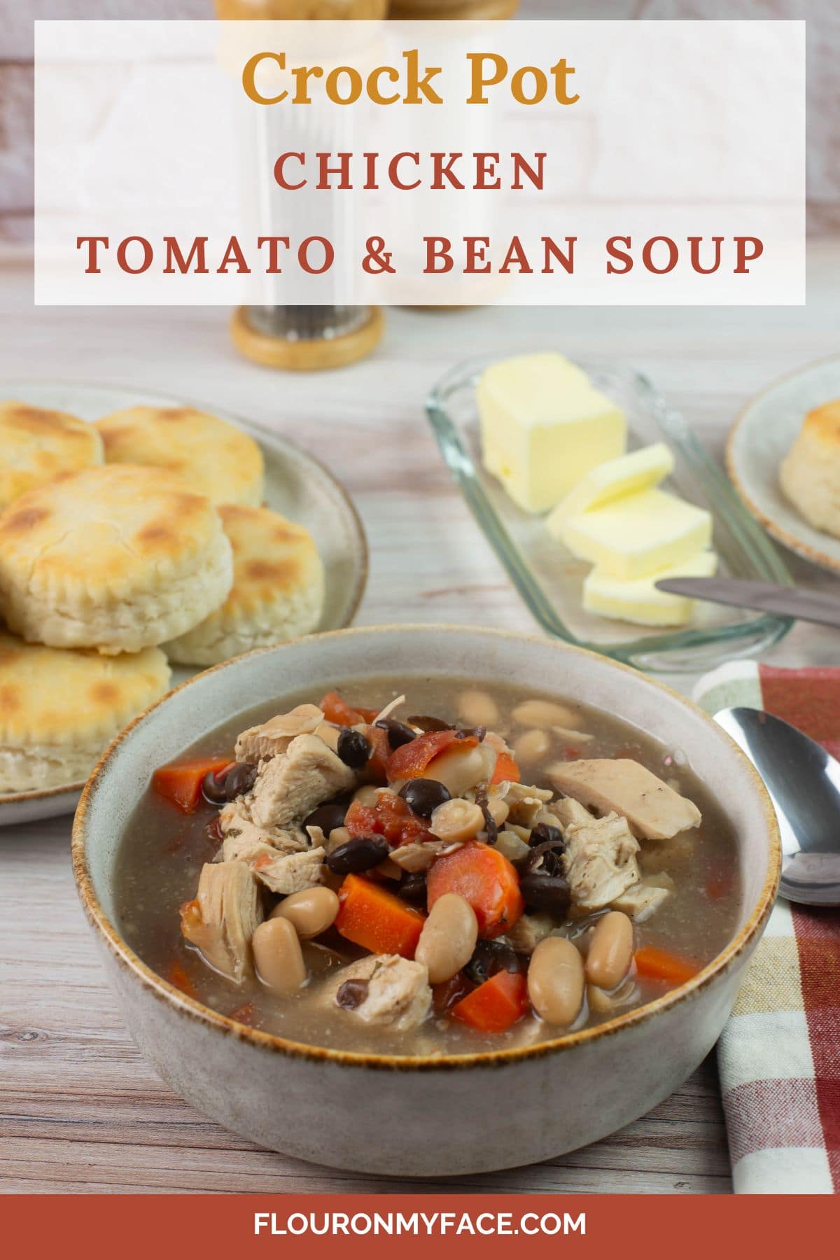 Vertical image of soup bowl with biscuits in the background.