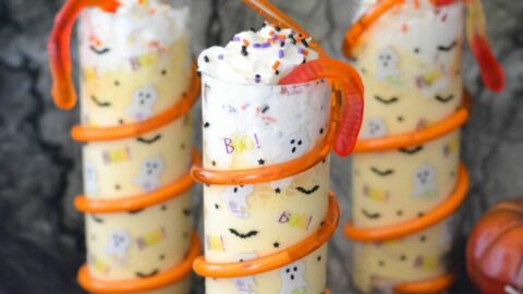 Three Halloween cups filled with an Orange Milkshake decorated with sprinkles.