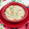 a red bowl filled with thick and creamy easy Crock Pot Chicken and Dumplings made with canned biscuits.