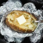 Crock Pot Baked Potato split down the middle with a pat of melting butter.