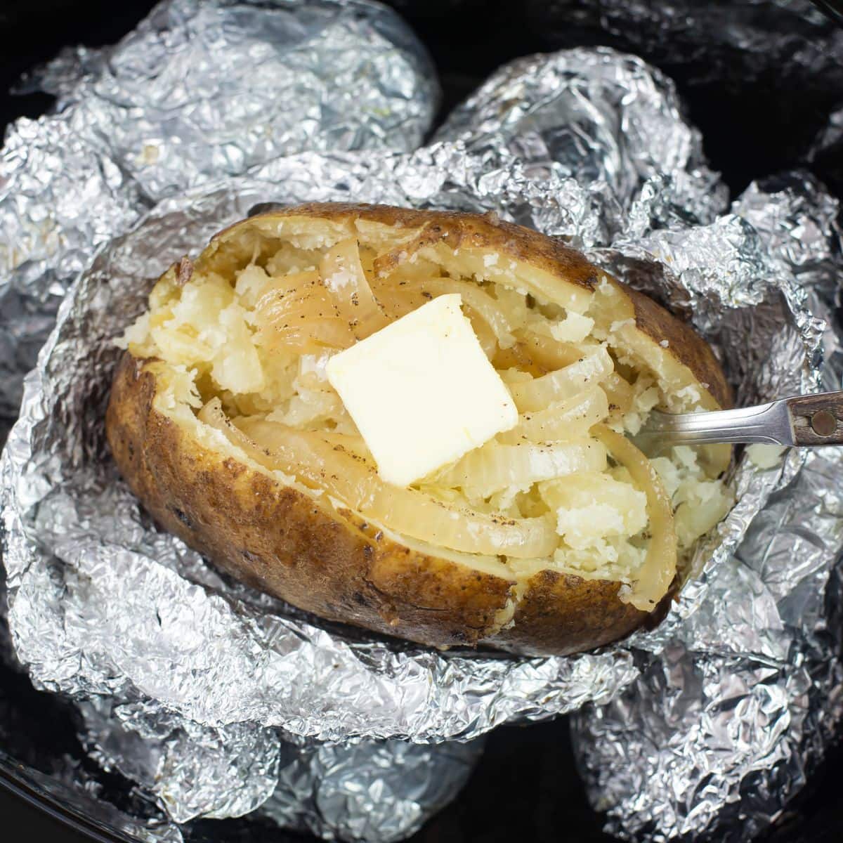 Crock Pot Baked Potato split down the middle with a pat of melting butter.