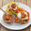 Stuffed bell peppers on a plate topped with sour cream and salsa.