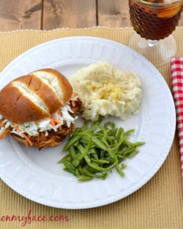 Raspberry Chipotle Pulled Chicken on a bun with sides.