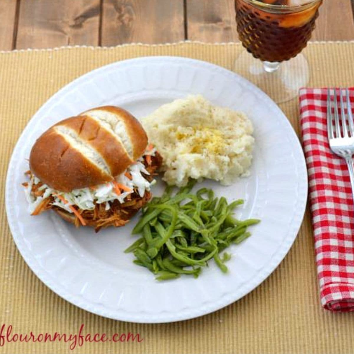 Raspberry Chipotle Pulled Chicken on a bun with sides.