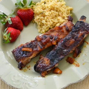 Hawaiian style BBQ Pork Ribs served on a green plate with fresh strawberries and yellow rice.