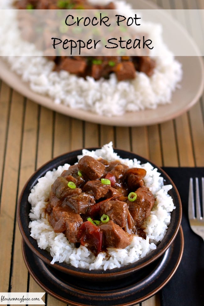 a brown glass bowl filled with my easy Crock Pot Pepper Steak recipe piled on a bed of tender white rice. 