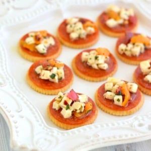 Pepperoni Bruschetta served on a cracker on a white plate.