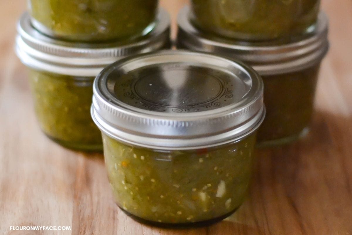 Canning jars filled with green salsa.