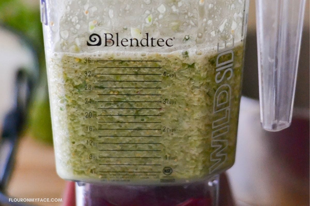 Green salsa ingredients chopped up in a blender. 