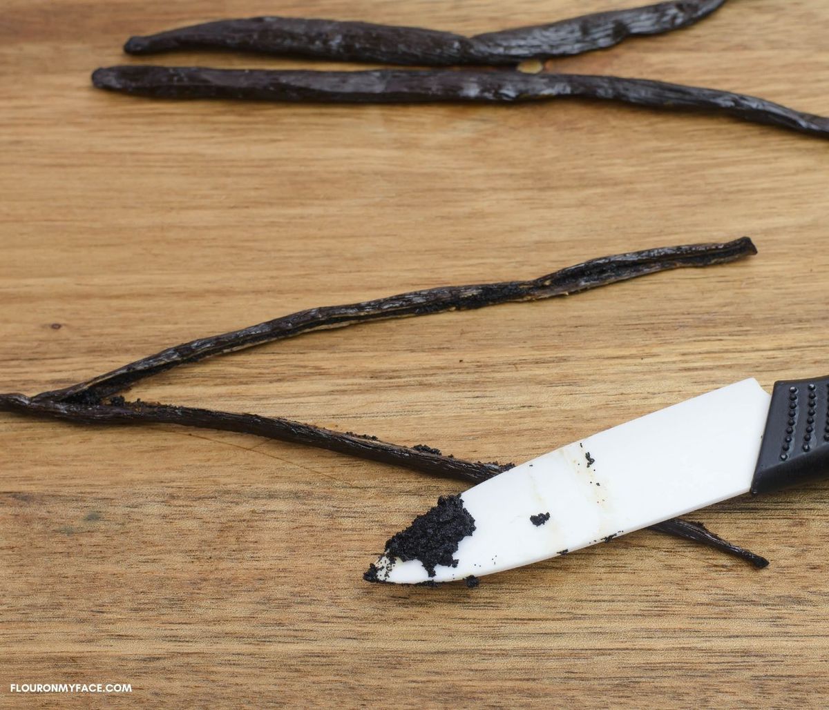 A vanilla bean that have been split and the seeds scraped on the tip of a knife.
