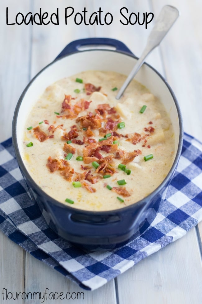  Blue cast iron soup bowl with a blue and white cloth napkin with a Crock Pot Loaded Potato Soup with crumbled bacon 