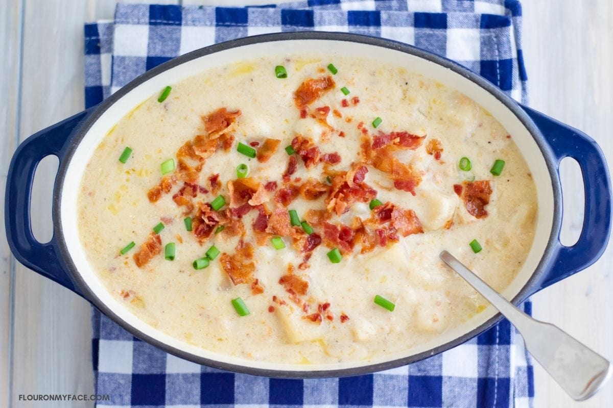 overhead photo of a blue cast iron pot with Loaded Baked Potato Soup.