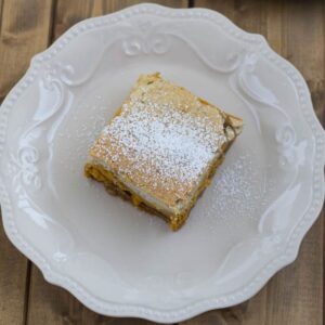 Three layer pumpkin cheesecake bar on a dessert plate.