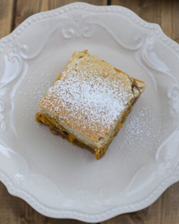 Three layer pumpkin cheesecake bar on a dessert plate.