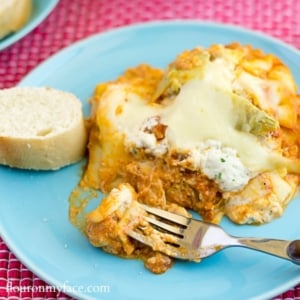 Chicken Artichoke Lasagna served with buttered Italian bread on a dinner plate.