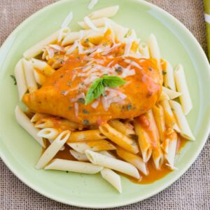 Boneless chicken breast slow cooked in Vodka sauce served over penne pasta on a dinner plate.