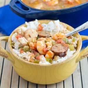 A yellow soup crock filled with white rice topped with Creole Jambalaya.