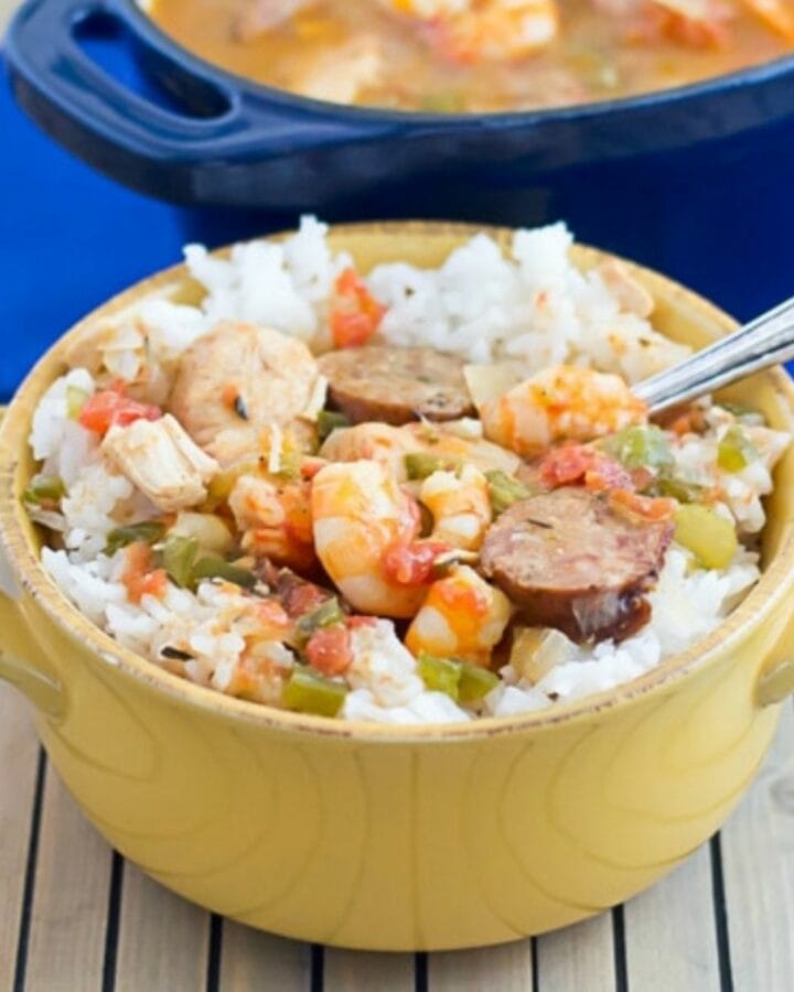 A yellow soup crock filled with white rice topped with Creole Jambalaya.