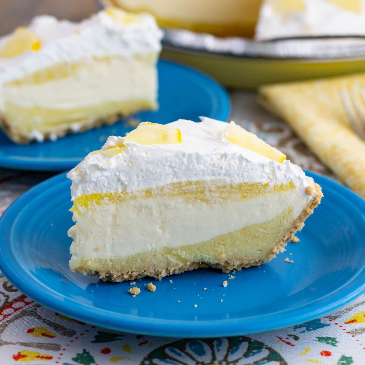 Four layer Lemon Cheesecake Pudding pie on a blue plate.