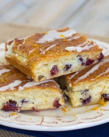 A stack of three cranberry orange crescent bars on a dessert plate.