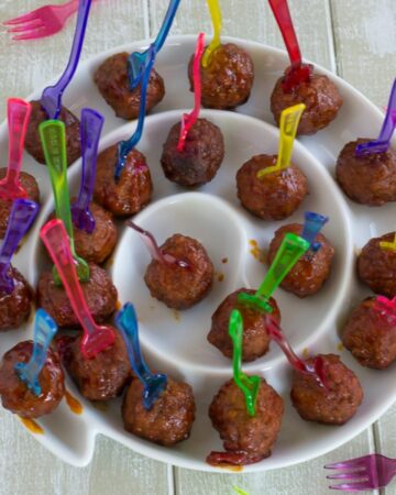 Peach Cranberry Meatballs on mini forks in a round serving platter.