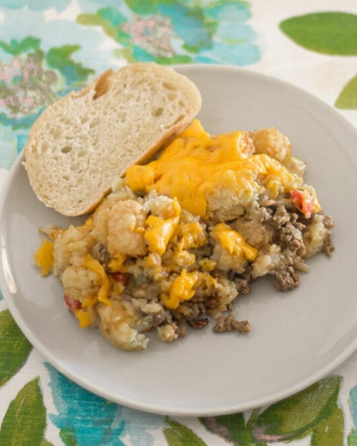 Serving crock pot Tater Tot Casserole with sliced Italian bread.