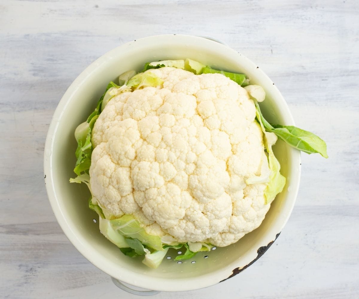 A rinsed head of cauliflower in a colander.