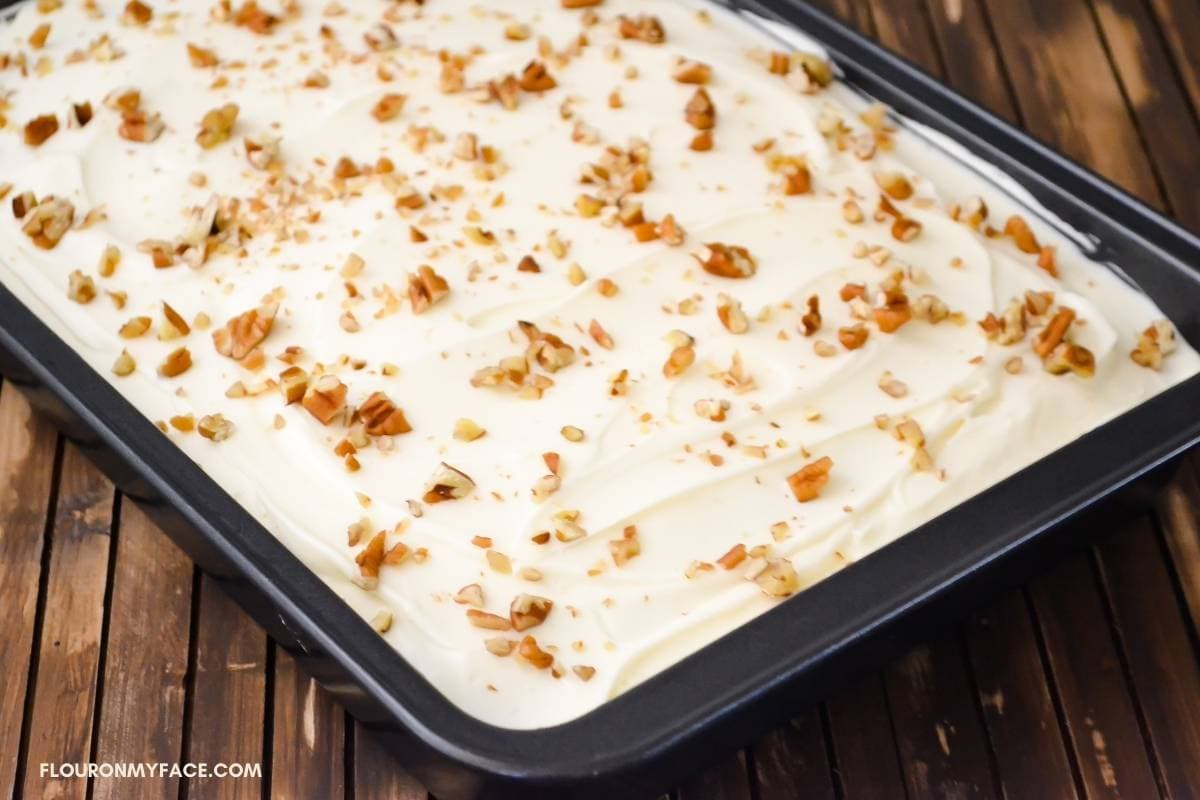 A carrot sheet cake frosted and sprinkled with nuts.
