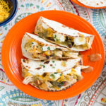 Chicken salsa served on warm tortilla with toppings on an orange plate