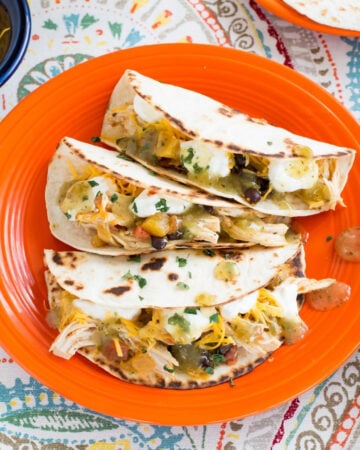 Chicken salsa served on warm tortilla with toppings on an orange plate