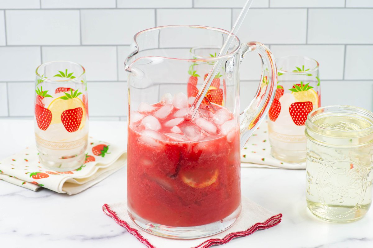 Mixing lemon juice and strawberry puree in a glass pitcher.