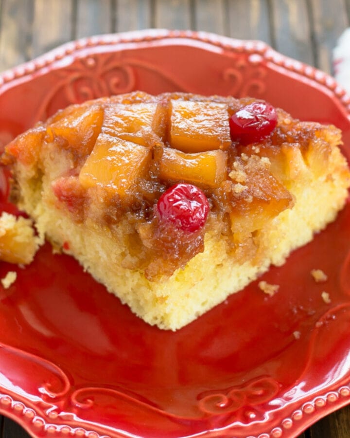 A slice of Crock Pot Pineapple Upside Down Cake on a red dessert plate