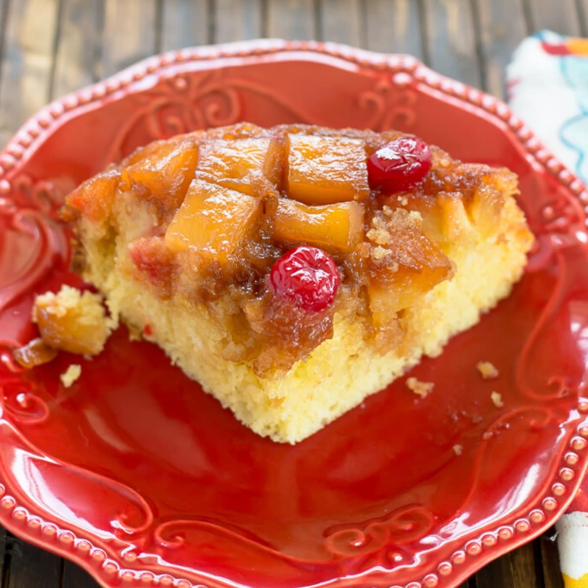 A slice of Crock Pot Pineapple Upside Down Cake on a red dessert plate