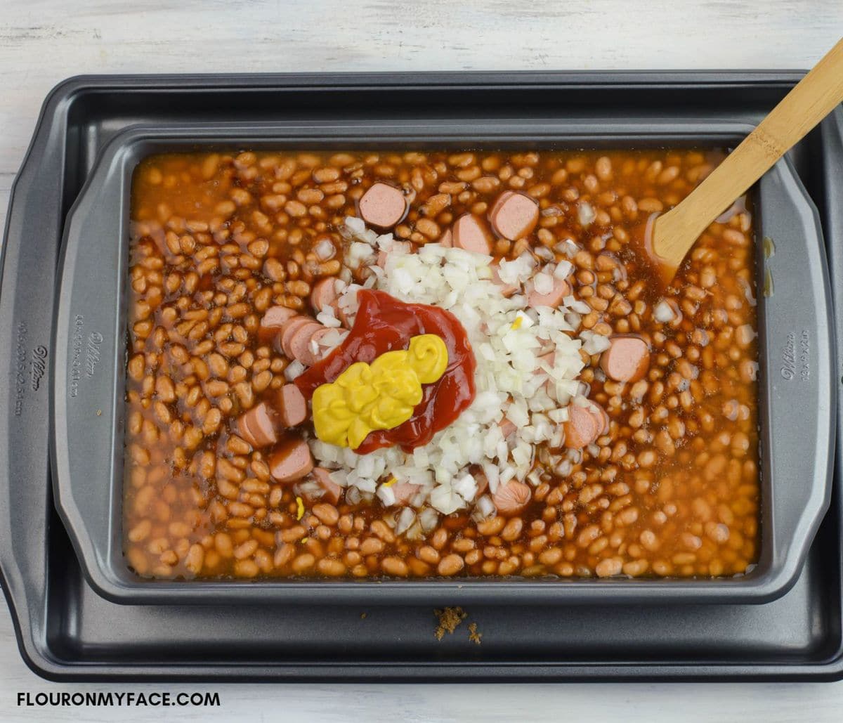 Combining the baked beans ingredients in a large baking pan.