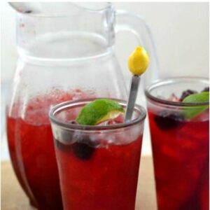 Blackberry Iced Cooler in glass with a pitcher beside.