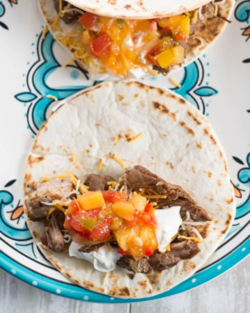 Tender shredded pork carnitas meat piled on a tortilla with salsa.