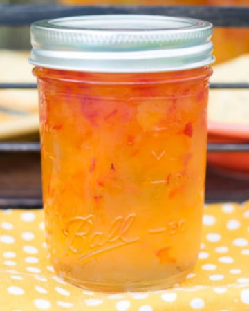 A canning jar filled with Habanero Apricot Jelly on a yellow cloth napkin.