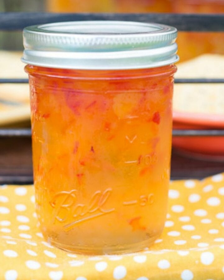 A canning jar filled with Habanero Apricot Jelly on a yellow cloth napkin.