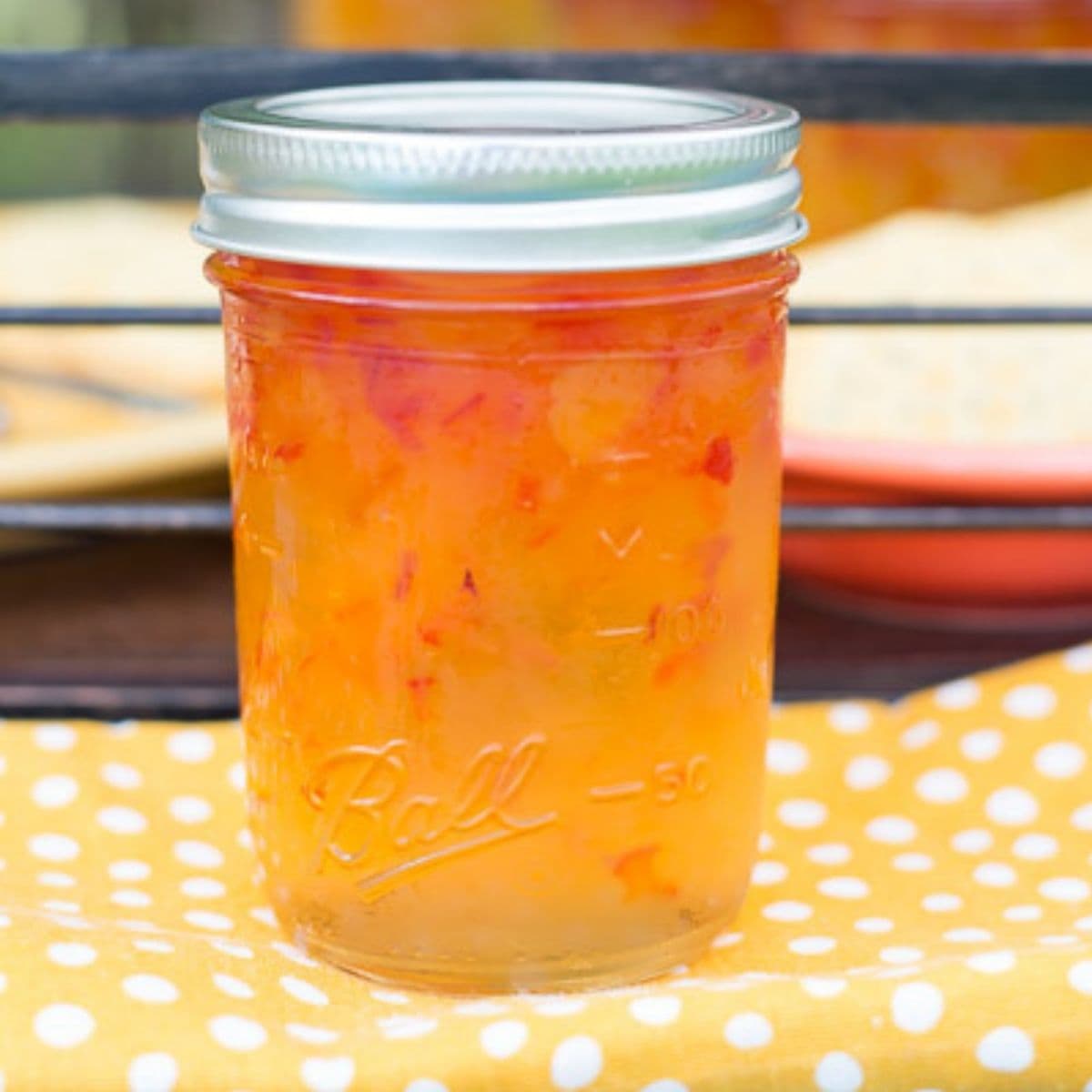 A canning jar filled with Habanero Apricot Jelly on a yellow cloth napkin.