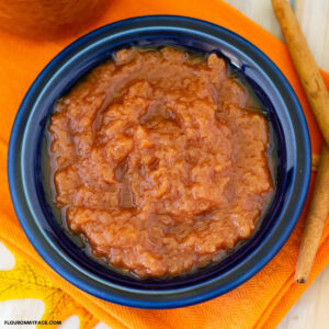 crock pot applesauce in a blue Fiestaware bowl on an orange Fall cloth napkin.