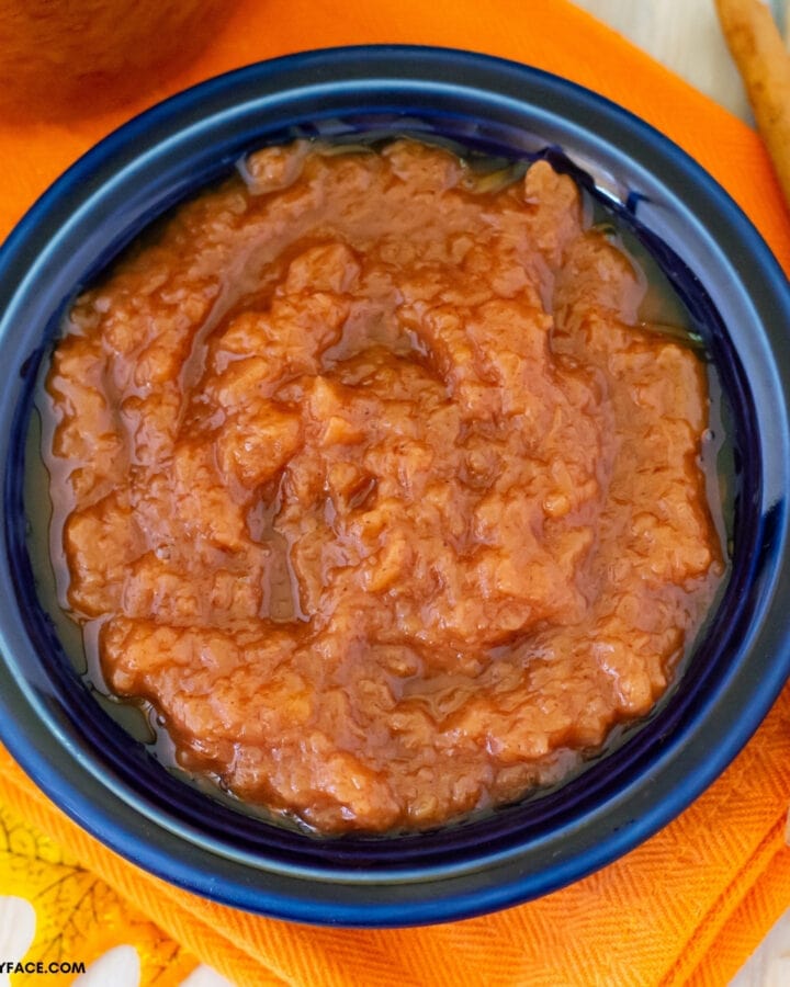 crock pot applesauce in a blue Fiestaware bowl on an orange Fall cloth napkin.