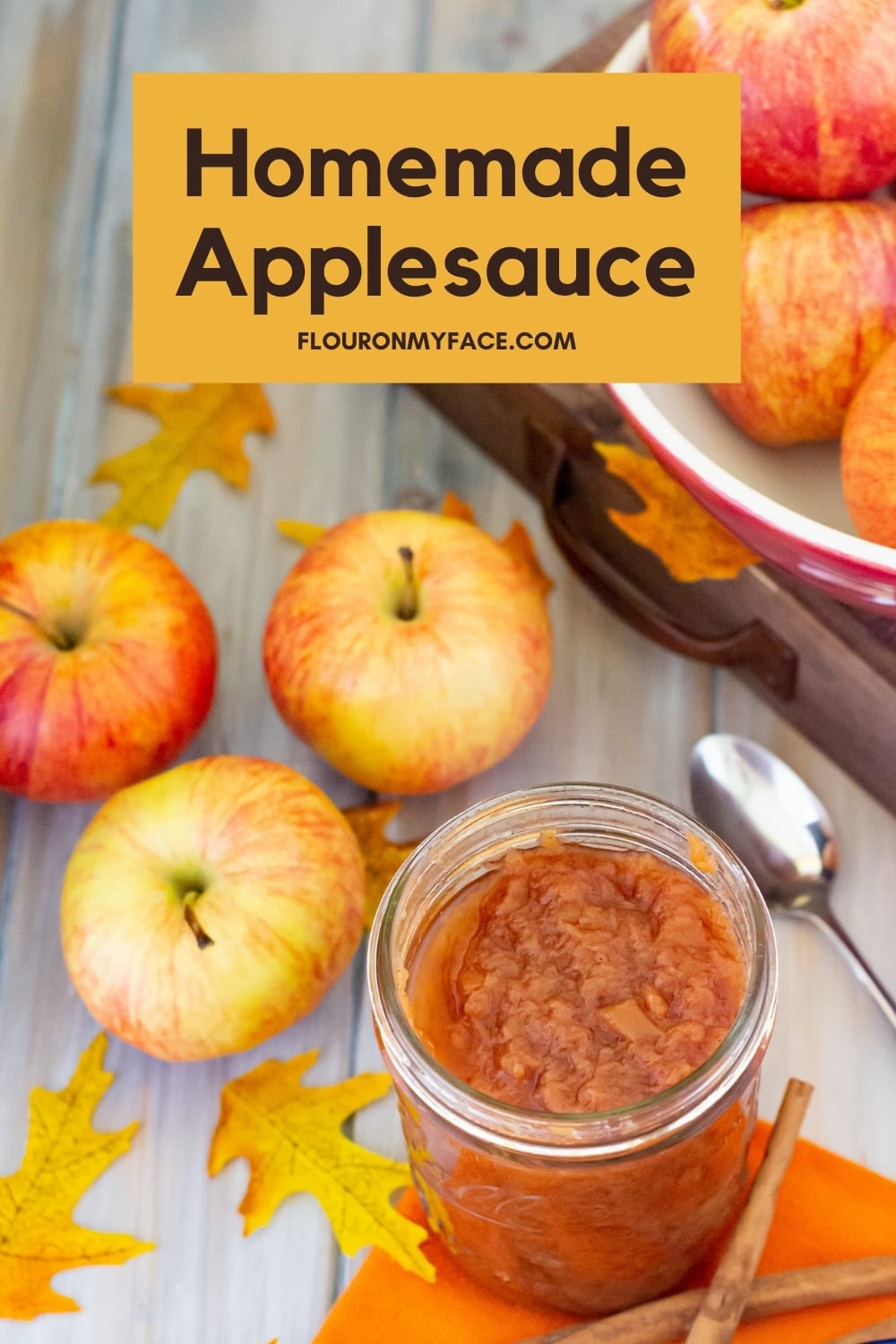 Homemade applesauce in a canning jars with three galla apples near by and a bowl in the background filled with apples