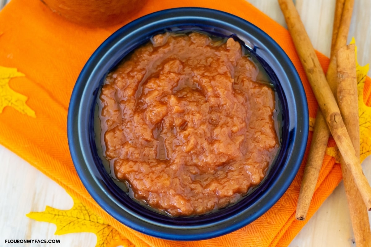 homemade applesauce in a blue bowl on an orange cloth napkin