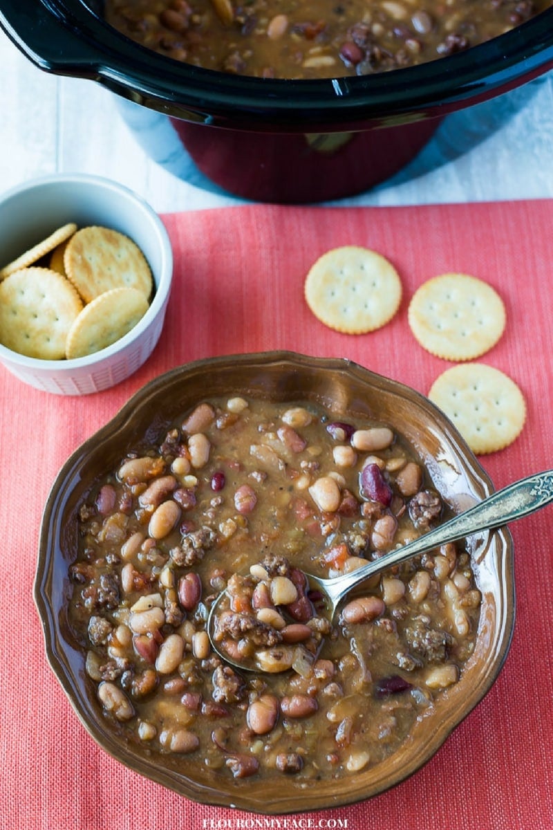 Crock Pot Hurst Bean Soup recipe in a brown bowl served with crackers.