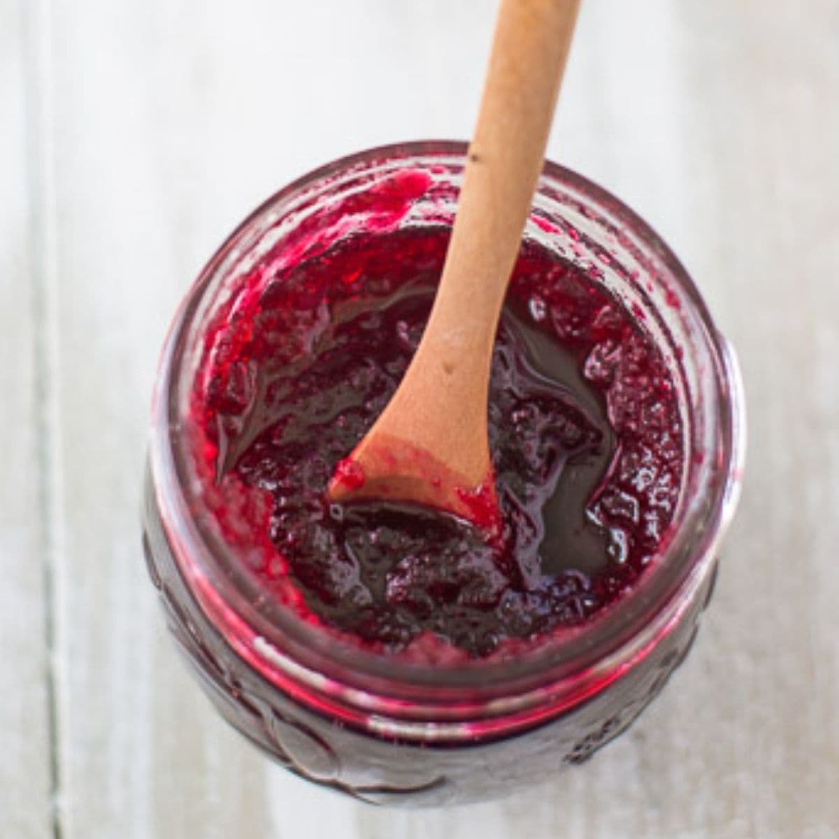 Overhead looking down into a glass canning jar filled with homemade cranberry sauce.