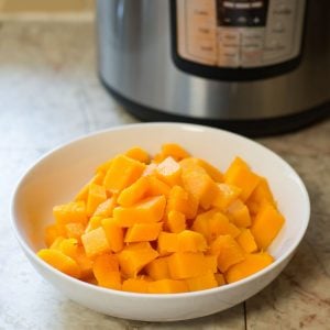Cubed Butternut Squash in a bowl with the Instant Pot appliance in the background