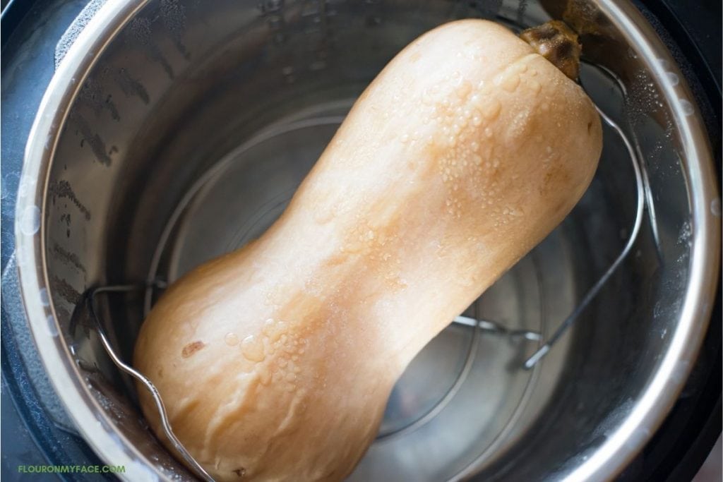 a whole unpeel and uncut butternut squash in the pot of a pressure cooker after cooking.